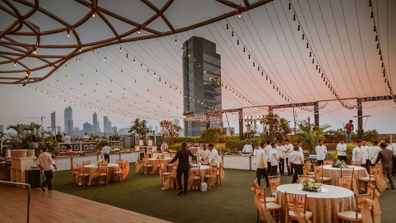 Mastering the First Impression: Your intriguing post title goes here Elegant rooftop event with tables and lights set against Mumbai skyline at sunset, India.